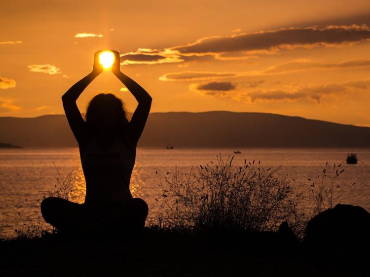 Vrouw beoefent yoga bij zonsondergang tijdens een vaar- en yogareis